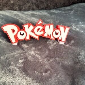 Red and white 3D print Pokémon Logo Display with stand attached